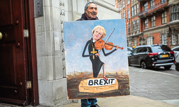 Political artist Kaya Mar stands with his painting depicting Prime Minister Theresa May playing a violin outside Millbank Studios in Westminster on January 16, 2019 in London.