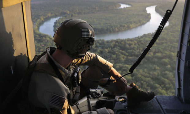 A US Customs and Border Protection agent searches for undocumented immigrants during a helicopter patrol over the Rio Grande at the U.S.-Mexico border in McAllen, Texas.