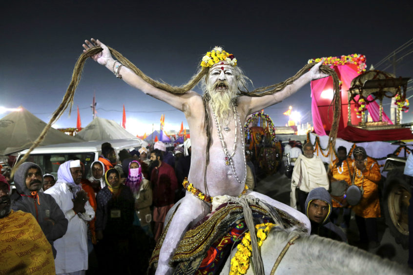 A naked Hindu holy man arrives on a horse back for ritualistic dip on auspicious Makar Sankranti day during the Kumbh Mela, or pitcher festival in Prayagraj, Uttar Pradesh state, India.