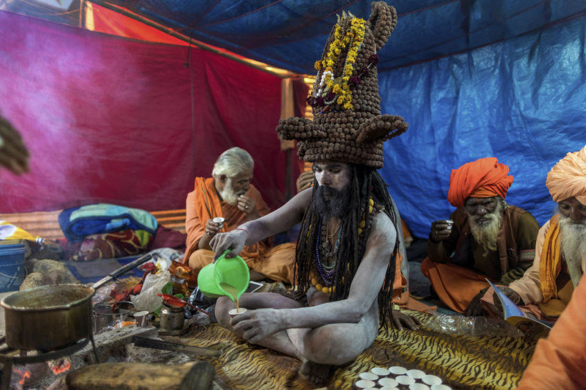 An Indian Naga Sadhu or a naked Hindu holy man prepares tea inside his tent during Kumbh Mela or pitcher festival at Sangam, in Prayagraj Uttar Pradesh state, India, .