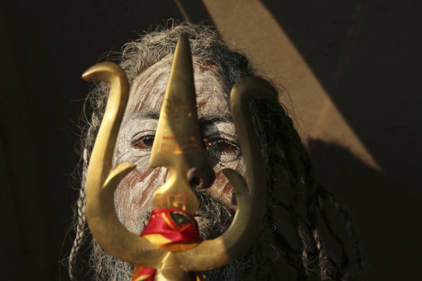 A Naga Sadhu stands with  trident as he participates in a procession towards the Sangam during the first 'royal entry' for the Kumbh Mela.