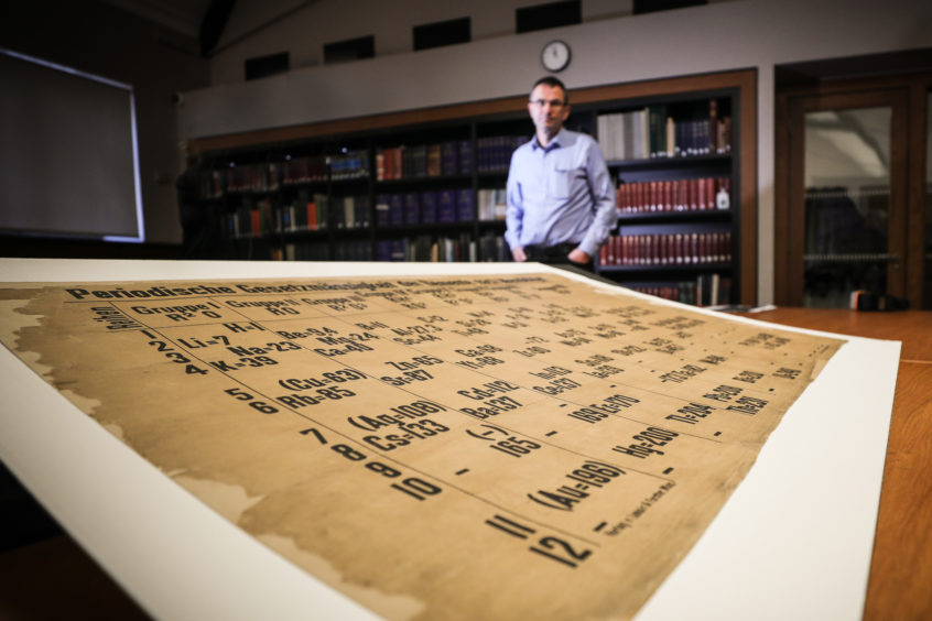 A Periodic table dating from the 1800's was discovered at University of St Andrews after a spring clean. Professor David O’Hagan stands with the recently conserved periodic table.