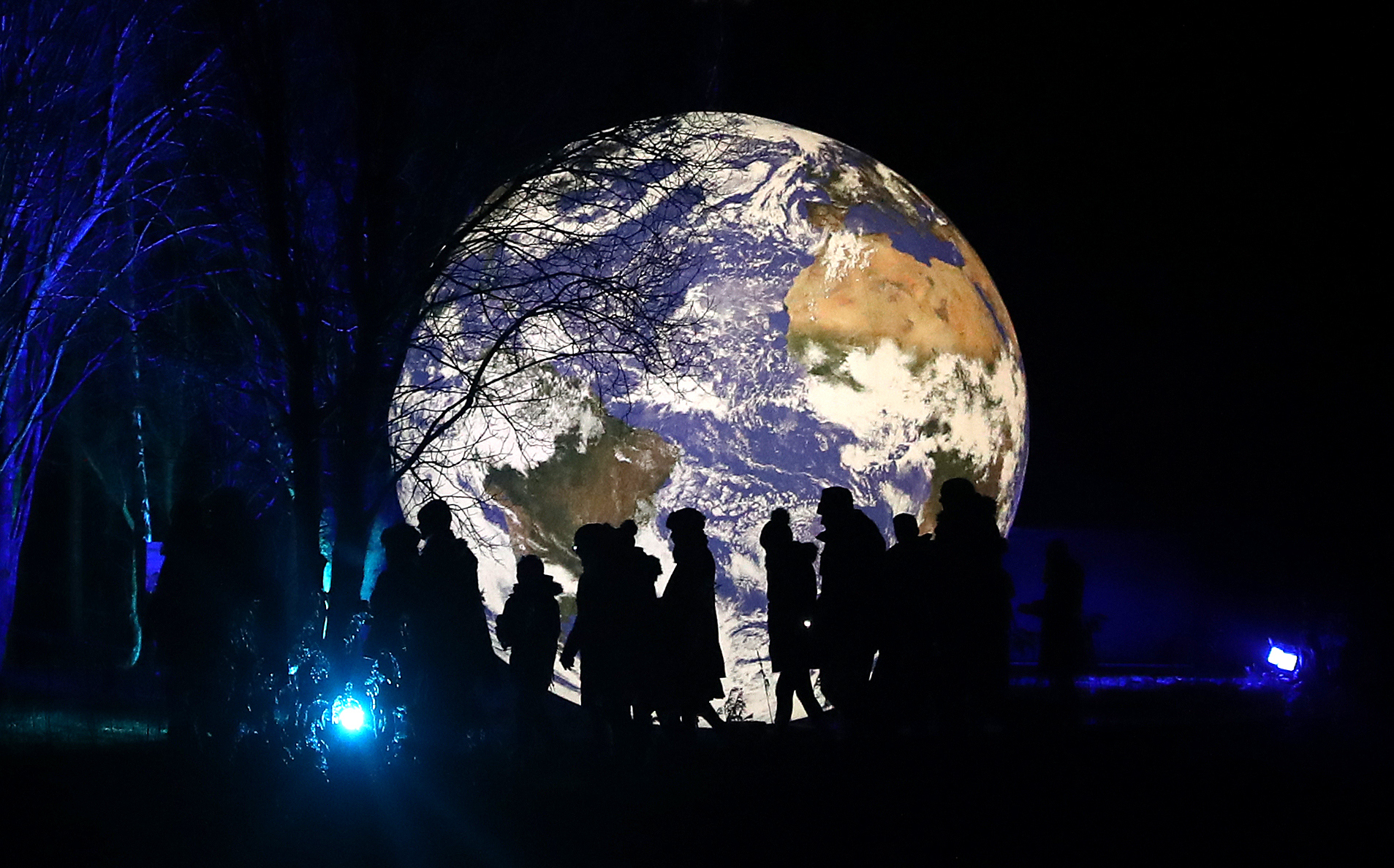 Visitors walks past the art installation Gaia, a seven-metre scale model of Earth created by artist Luke Jerram.