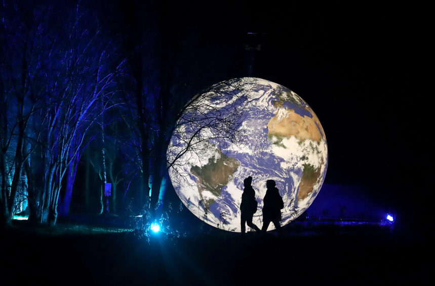 Visitors walks past the art installation Gaia.