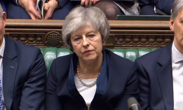 Prime Minister Theresa May listens to Labour leader Jeremy Corbyn speaking after losing a vote on her Brexit deal in the House of Commons, London.