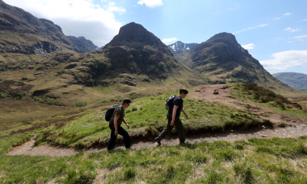 Walkers near the Three Sisters mountain range in the Highlands.