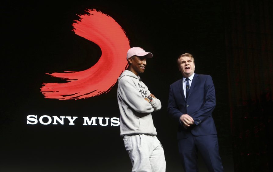 Rob Stringer, right, CEO of Sony Music Entertainment, surprises the audience as musician Pharrell Williams walks on stage at the Sony news conference.