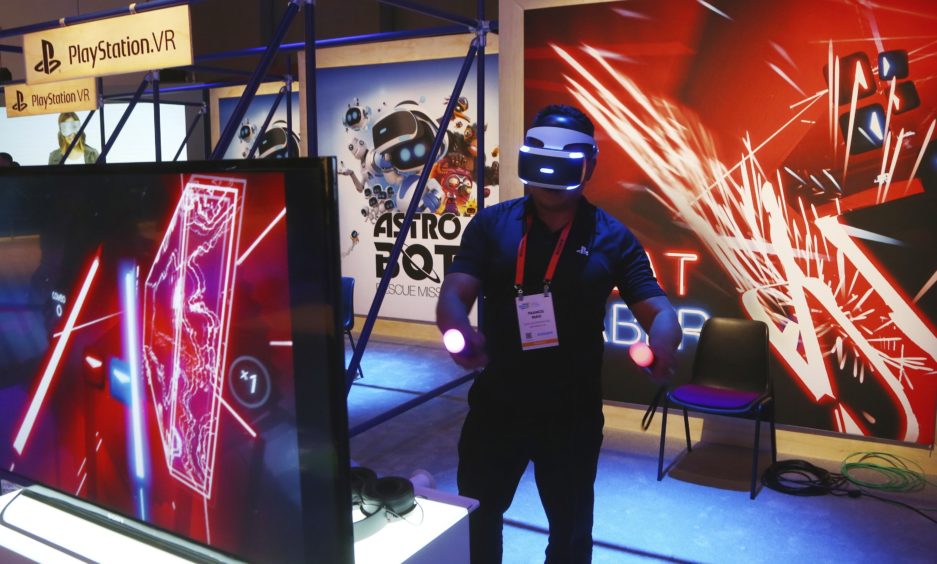 A CES attendee plays the PlayStation VR Beat Saber game inside the Sony display area.