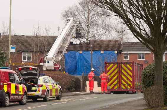 Staffordshire Fire and Rescue personnel stand outside a tarpaulin covered property with a burnt out roof at the scene of a deadly house fire on February 5, 2019 in Stafford, England.