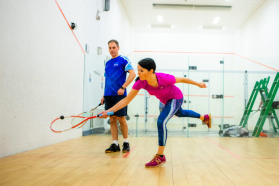 Gayle has a bash at playing squash under the watchful eye of coach Mark Beaumont.