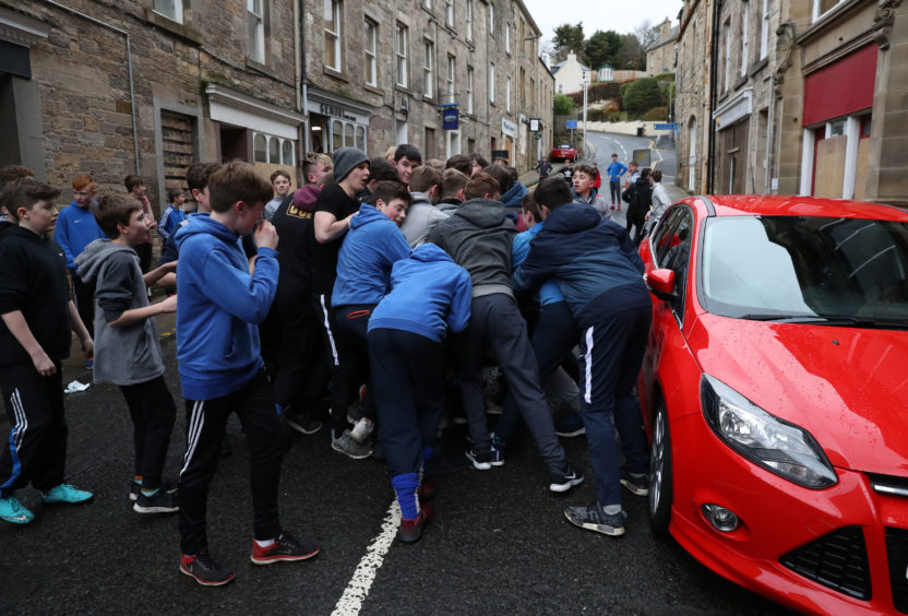 Boys tussle for the leather ball next to a car during the annual 'FasternÕs E'en Hand Ba' event on Jedburgh's High Street in the Scottish Borders.