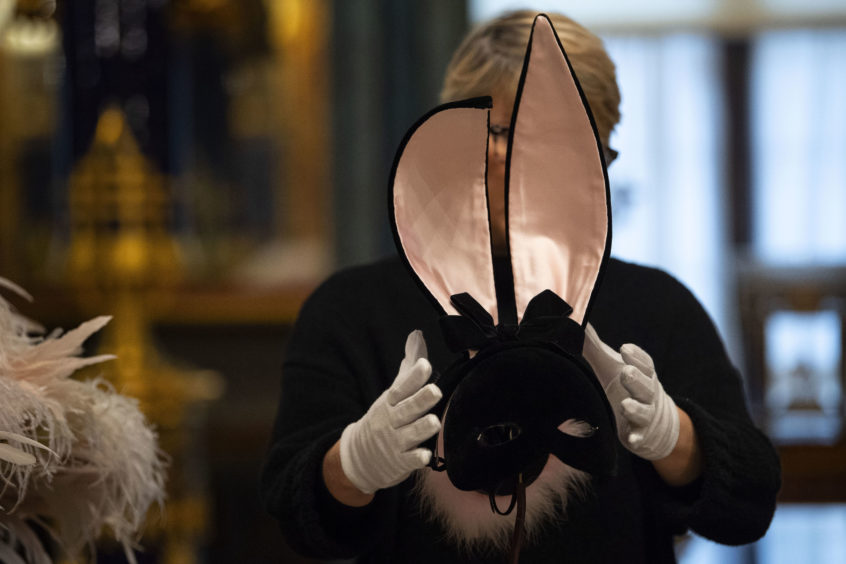 A member of staff adjusts a hat designed for Kate Moss (2014).
