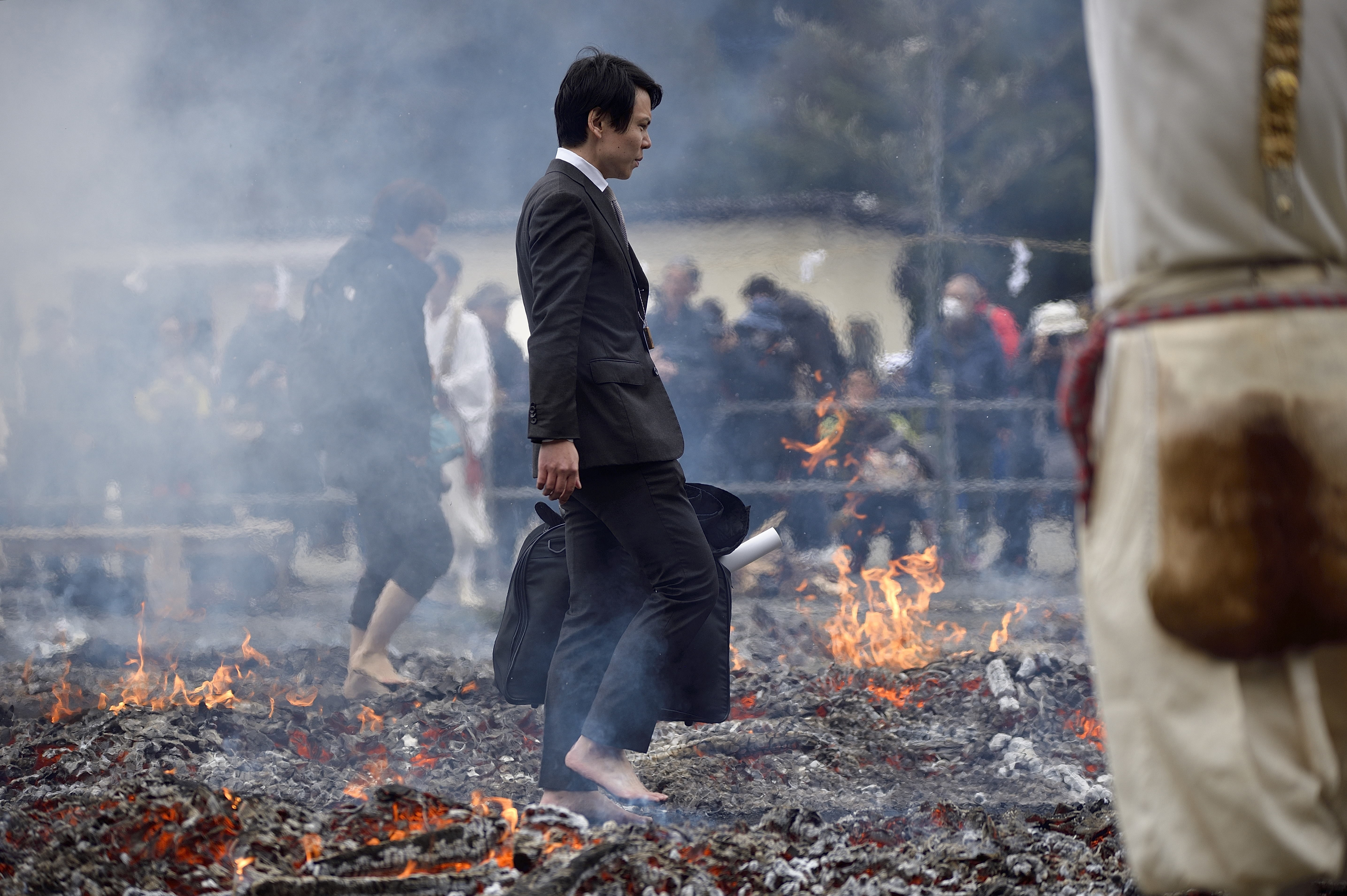 A salaryman walking barefoot over the hot coals, and through flames which purify by burning all defilements away, prays for protection against sickness and calamity and for safety within the family during the Hiwatari fire walking festival in a fire ritual called Saito Goma-ku at Yakuo-in temple in Takaosanguchi in Tokyo, Japan.