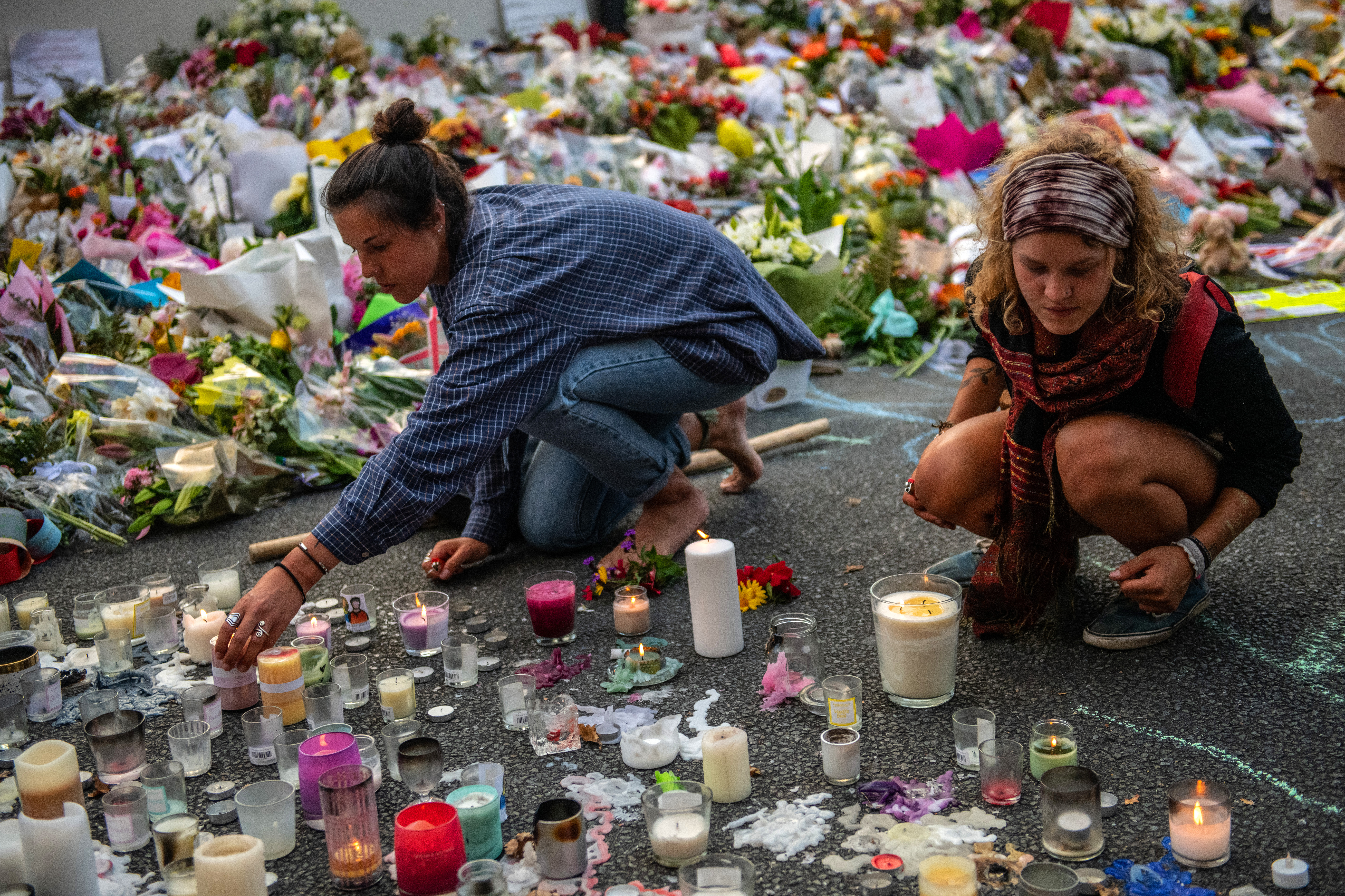 Women light candles next to flowers and tributes near Al Noor mosque on March 19, 2019 in Christchurch, New Zealand.