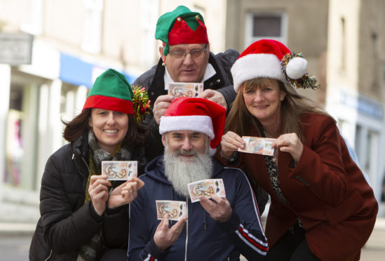 Forfar Action Network chairman Stuart Pirie (centre front) with FAN members, (clockwise) Jacqui Garvie, Tom O'Brien and Fiona Mulligan with five £10 notes for the 'Forfar Fifty'.