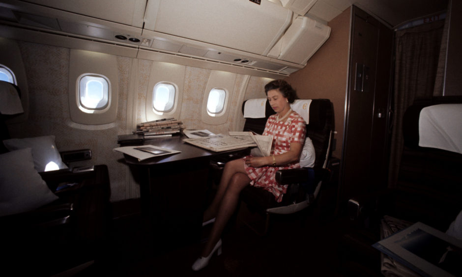 Queen Elizabeth II reading newspapers during her flight home on Concorde from Bridgetown, Barbados, after her Silver Jubilee tour of Canada and the West Indies.