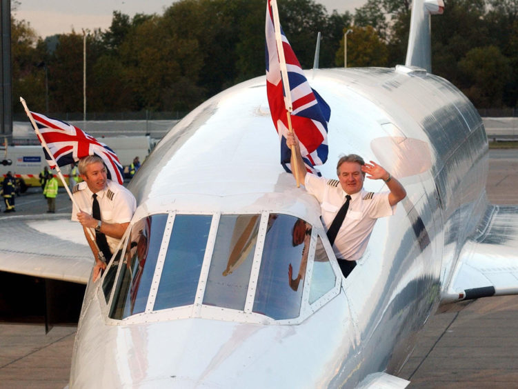 Captain Mike Bannister (R) and Senior First Officer Jonathan Napier (L) waving from the cockpit of a British Airways Concorde after landing at London's Heathrow Airport, on the day that the world's first supersonic airliner retired from commercial service.