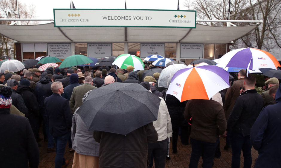 Racegoers shelter from the rain as they wait for the gates to open. Andrew Matthews/PA