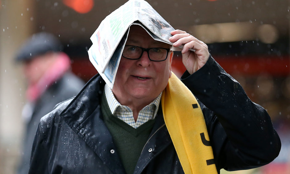 A racegoer shelters from the rain. Nigel French/PA