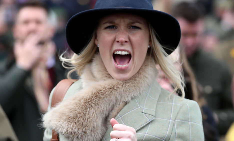 A racegoer reacts as she watches the action in the stands. Andrew Matthews/PA