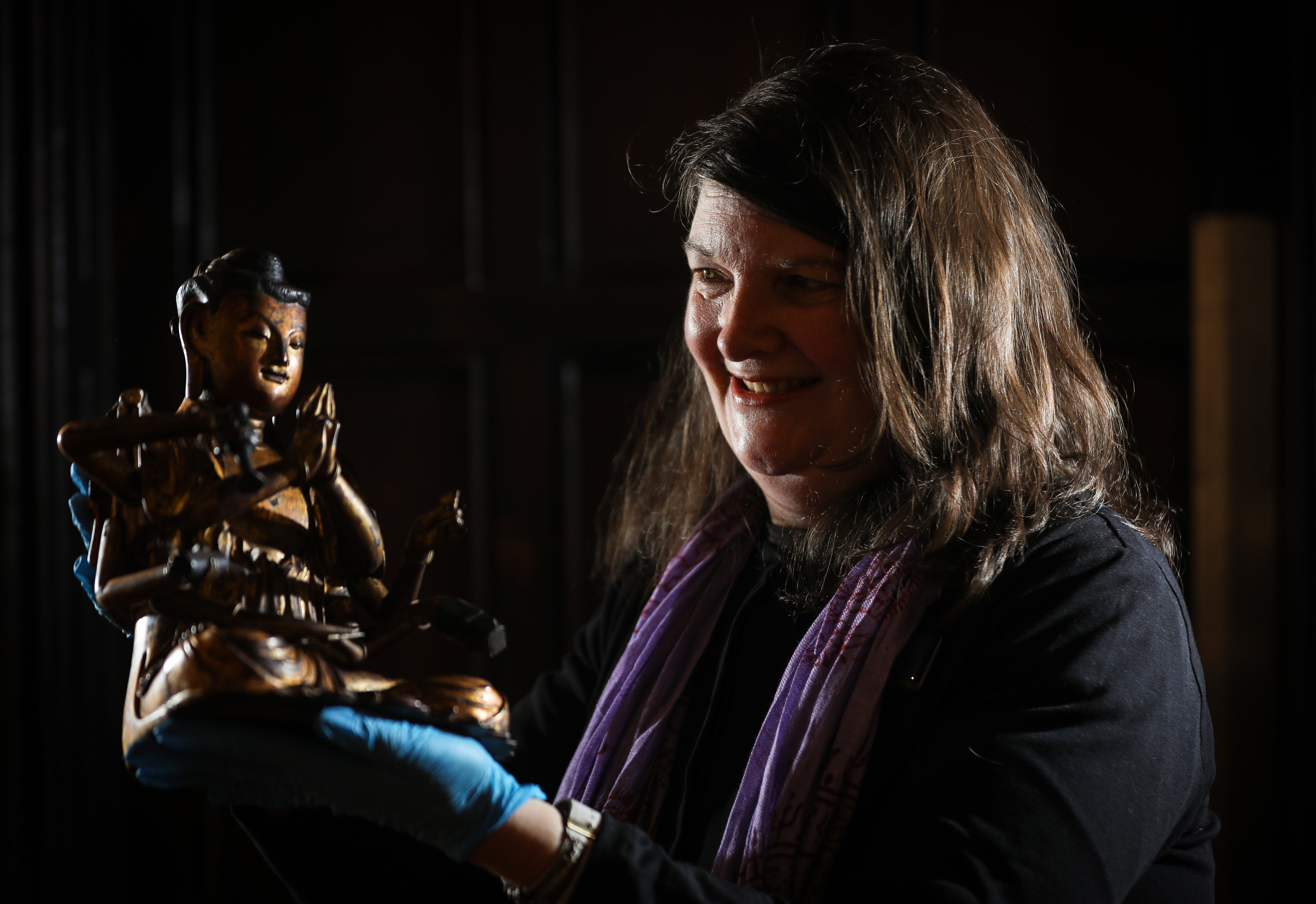 Christina Donald, curator of early history with an altar figure of Guanyin