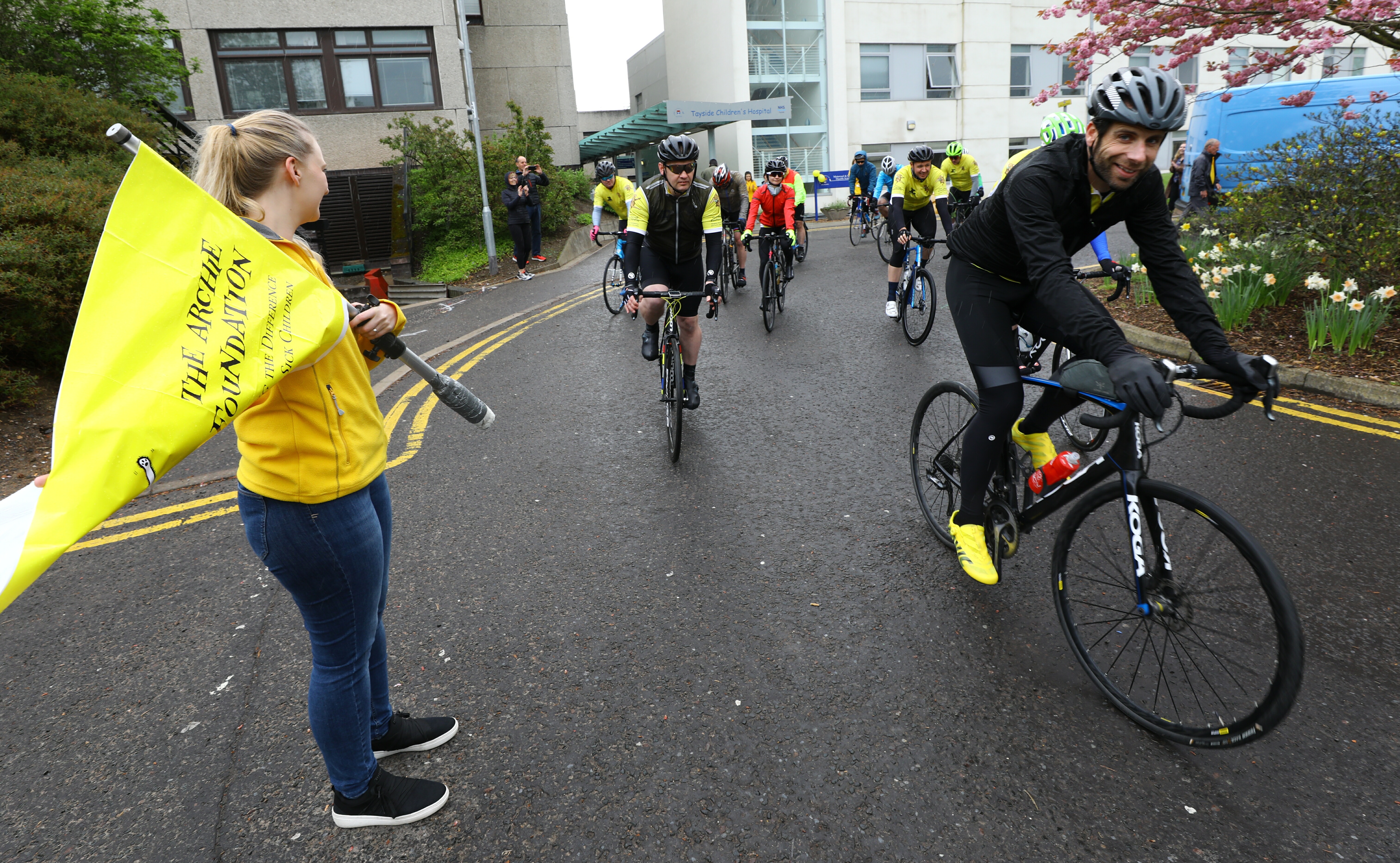 Claire Bush - National Events Manager,  flagging the cyclists off, as Mark Beaumont leads the way, on their charity ride for ARCHIE to Inverness, then Aberdeen. Friday 26th April 2019.