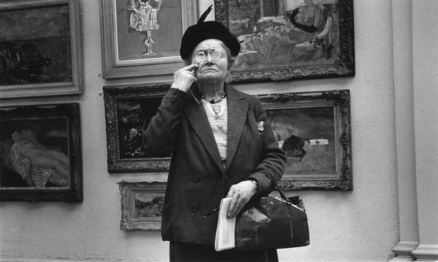 An elderly woman peers at a painting through a magnifying glass at the Tate Gallery, London. Original Publication: Picture Post