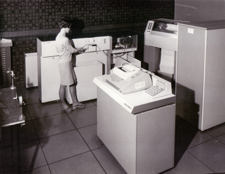 A member of staff operating an early computer (possibly an Elliott 4100) at Dundee College of Technology