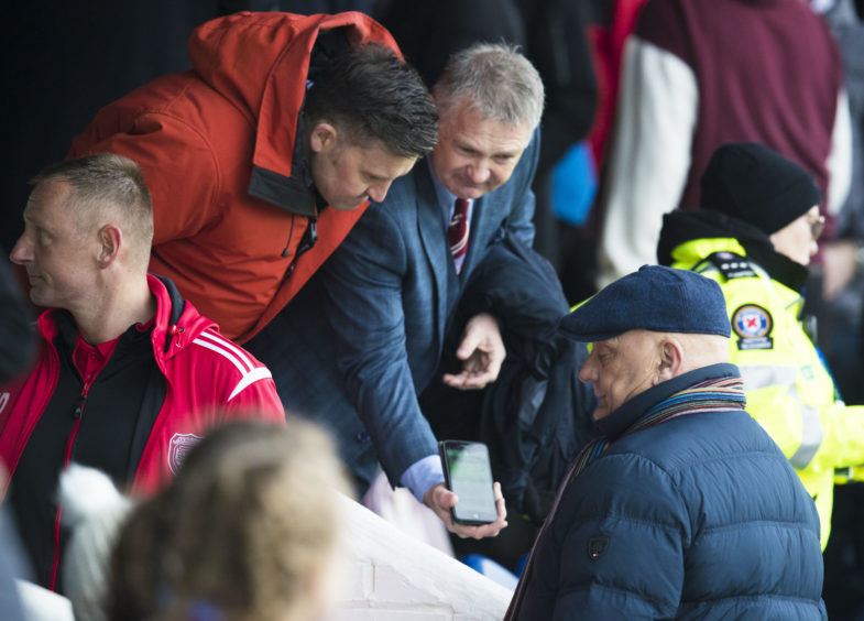 Arbroath manager Dick Campbell (R) is shown the score from the Stenhousemuir v Raith Rovers match.
