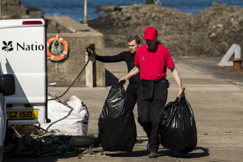Volunteers haul rubbish from the Causeway Maid boat onto the dock at Ballintoy Harbour during a litter pick around the coastline of the Giant's Causeway in Northern Ireland.