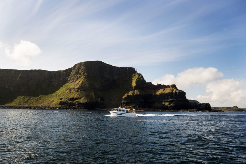 Aquaholics boat passing Port na Spaniagh during a litter pick around the coastline of the Giant's Causeway in Northern Ireland.