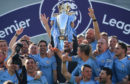 Manchester City manager Pep Guardiola holds the winners' trophy aloft after the Premier League match between Brighton & Hove Albion and Manchester City.