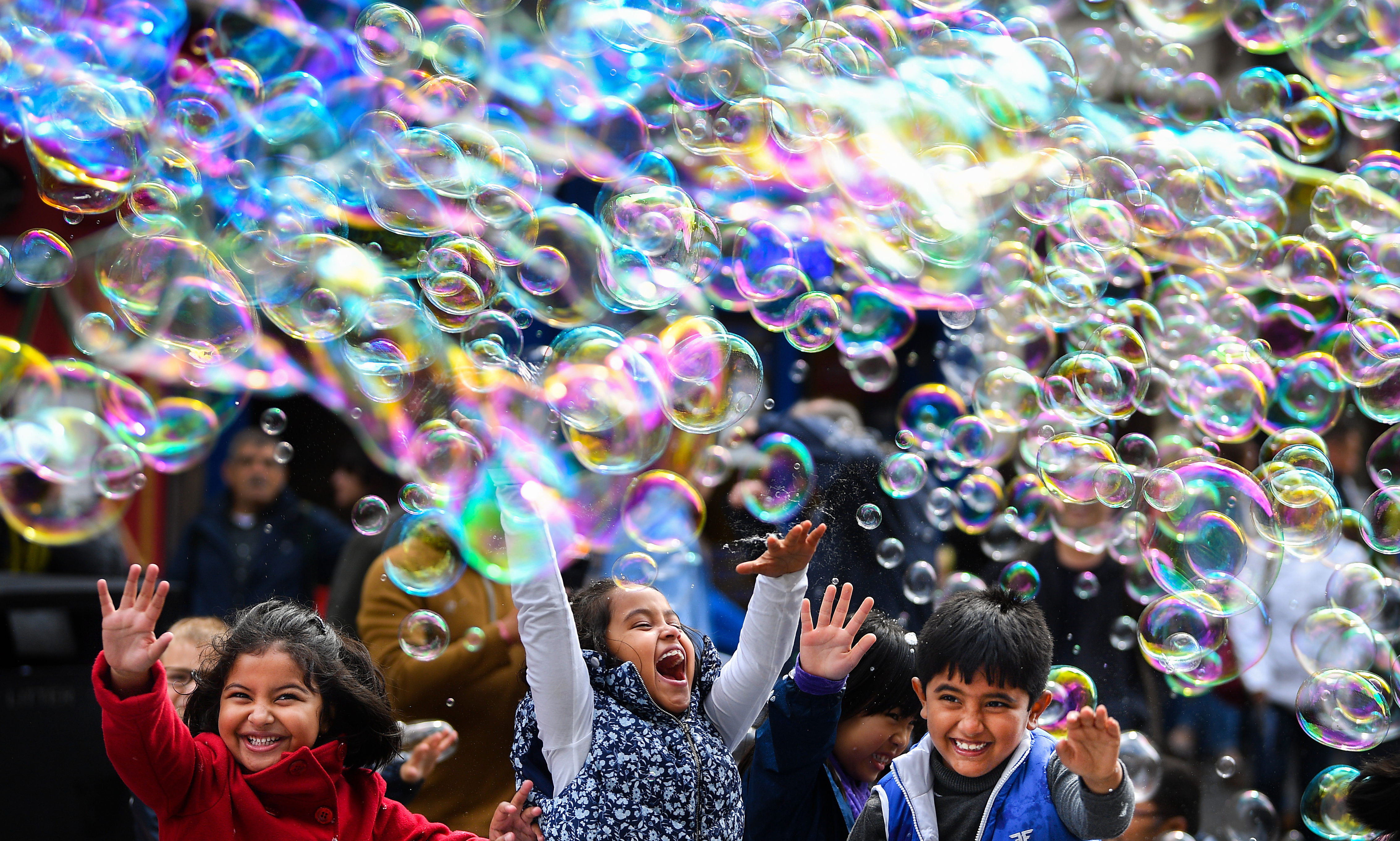 A street performer on the Royal Mile entertains members of the public with a mass of bubbles in Edinburgh.