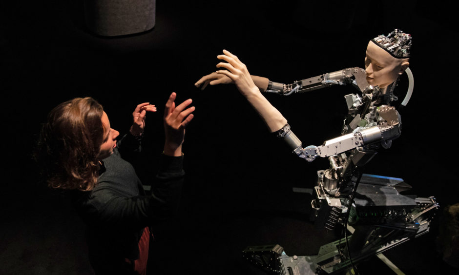 A women interacts with 'Alter', a machine body with a human like face and hands who learns through interplaying with the surrounding world.