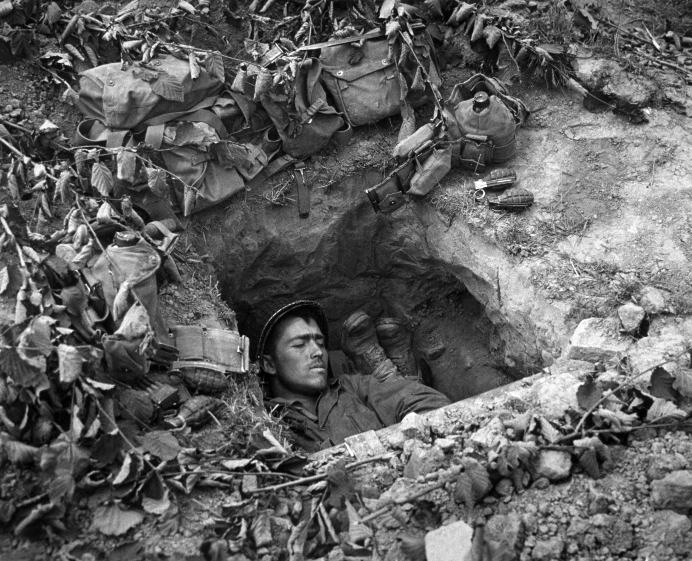1944: An American GI asleep in a trench in Normandy.