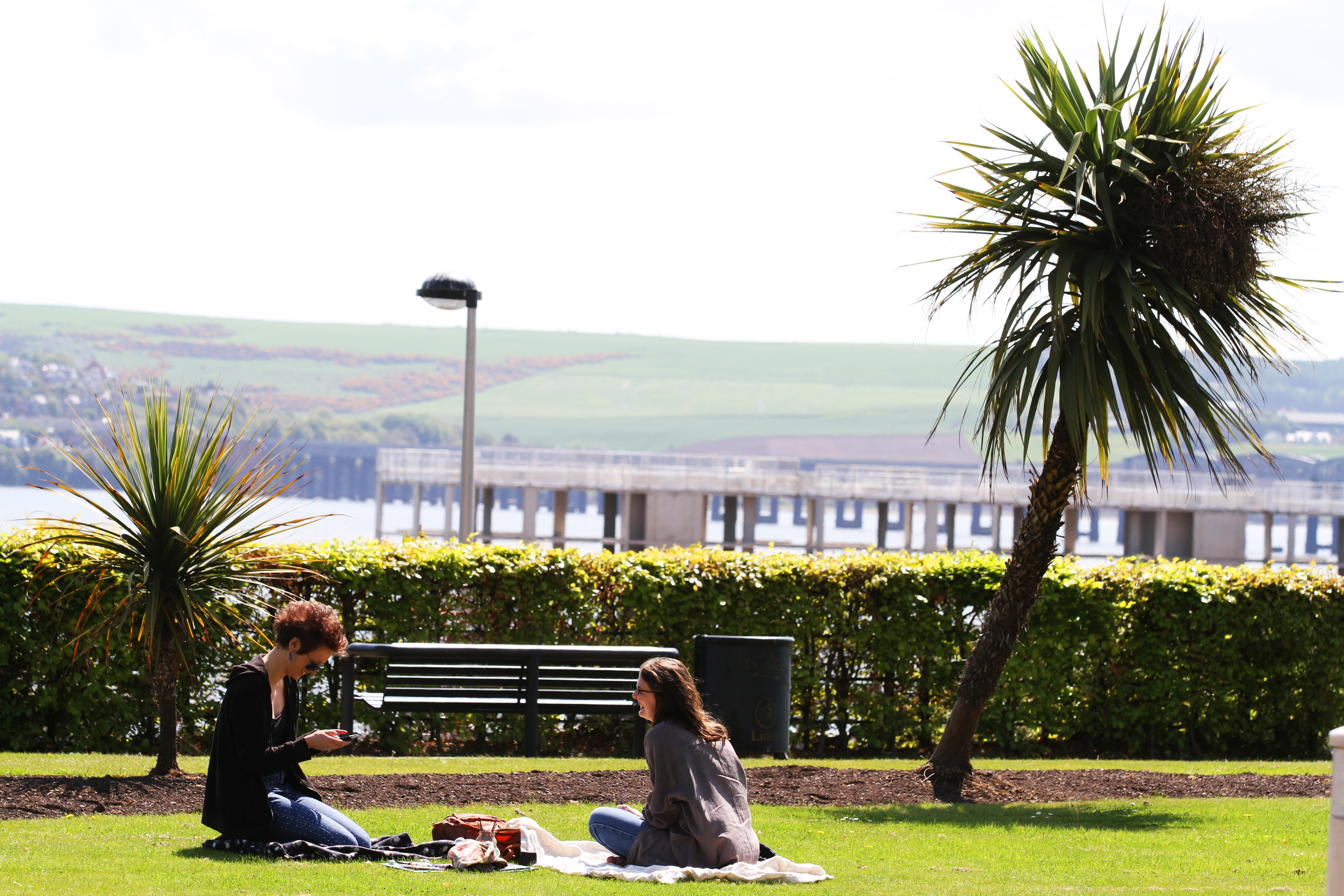 Two girls have a picnic in the sun amongst the palm trees on Perth Road.