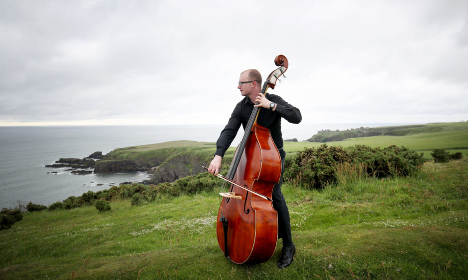 Musician Scott Matheson from the #iPlay4Peace crowdsourced global orchestra plays his double bass on the Black Hill near the Stonehaven War Memorial in Aberdeenshire, an unfinished Greek temple representing the unfinished lives taken by war, ahead of the 100th anniversary of the signing of the Treaty of Versailles.