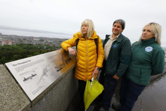 Councillor Anne Rendall, Colin Donald and Laura Jane Blackie, who illustrated the plaques, - both DCC Countryside Rangers, beside one of the new plaques at the top of Dundee Law.