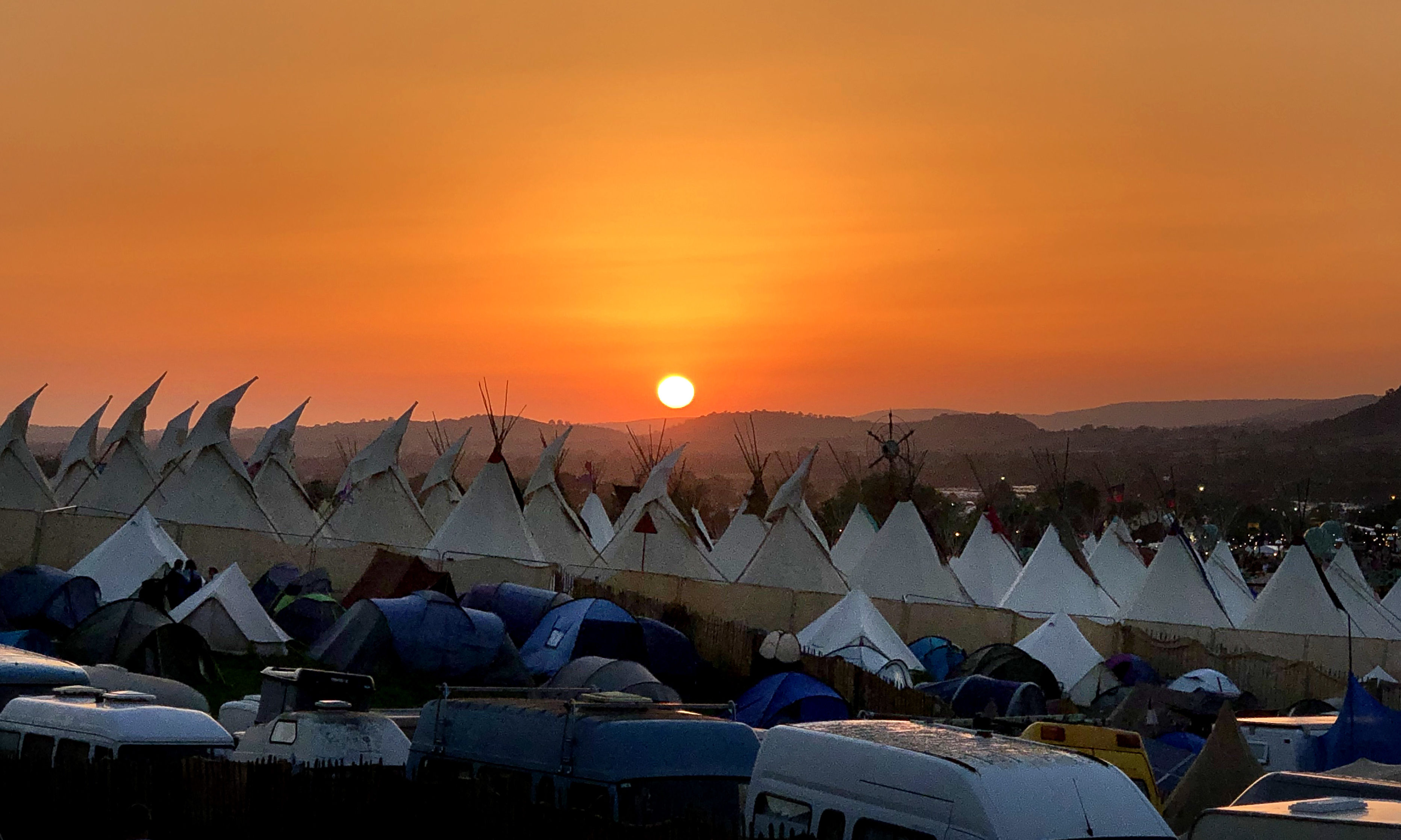 Festival goers watch the sunset during day two of Glastonbury Festival at Worthy Farm, Pilton on June 27, 2019 in Glastonbury, England.
