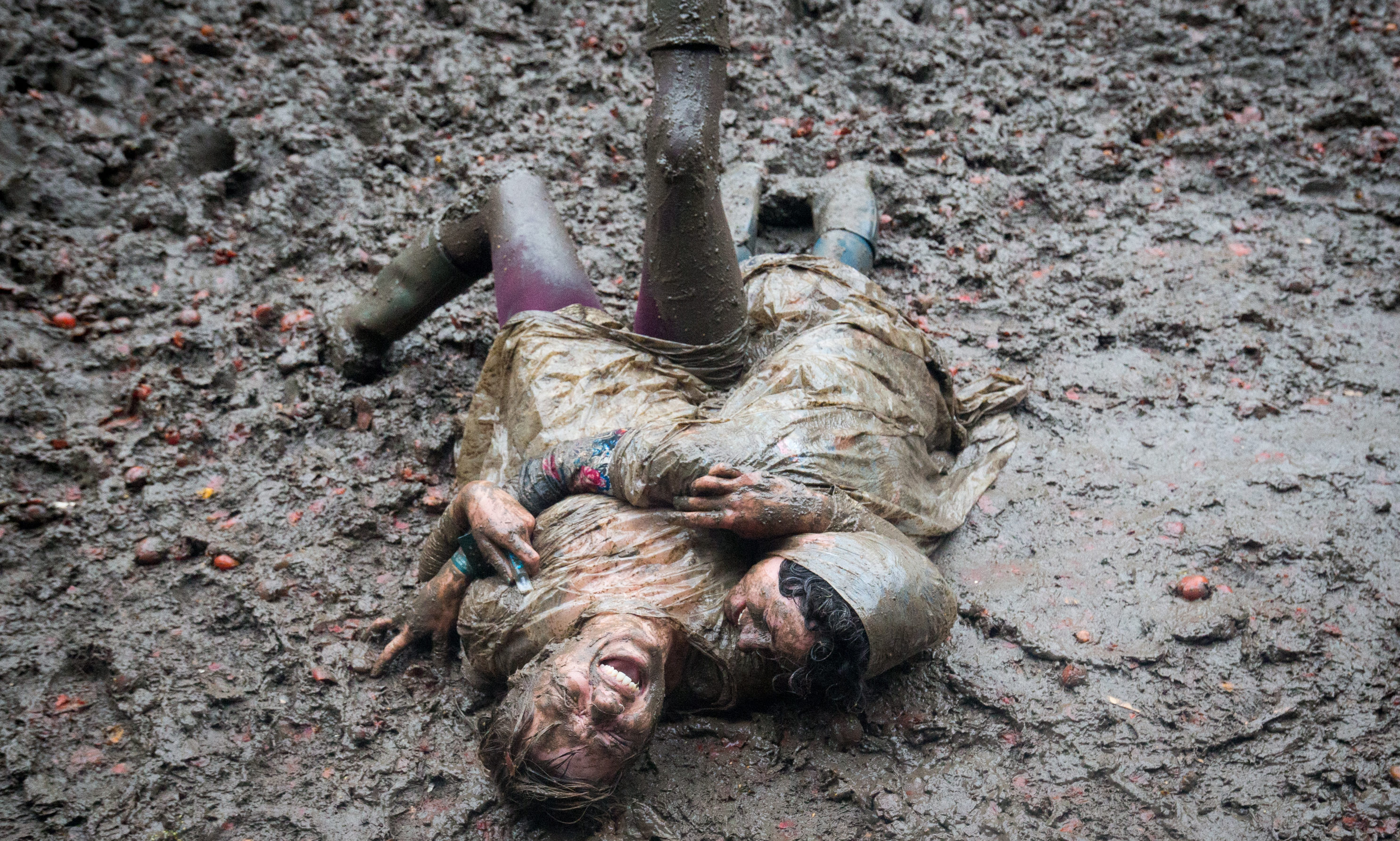 Two festival revellers roll in the mud after they took part in a tomato fight at the Glastonbury Festival 2016. (Photo by Matt Cardy/Getty Images)