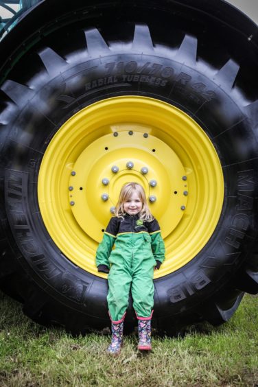 Holly Hughes being dwarfed by a John Deere tractor tyre.