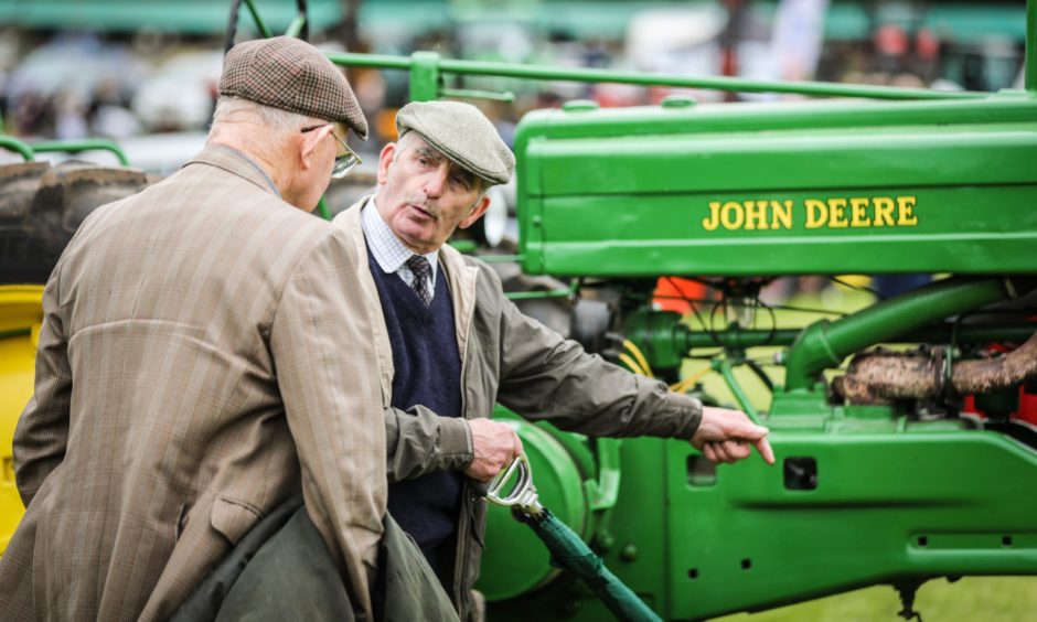 People inspecting the vintage tractors.