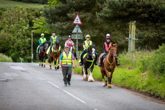 Newton Farm Stables manager Caroline Andrew and Councillor Jonny Tepp leading horses on a country road.