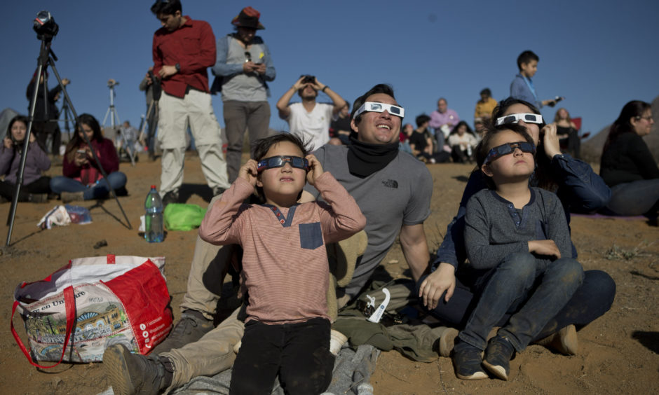 Tens of thousands of tourists and locals gaped skyward Tuesday as a rare total eclipse of the sun began to darken the heavens over northern Chile.