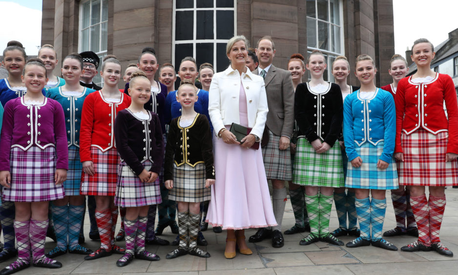 The Earl and Countess of Forfar pose for a photograph with dancers after watching a highland dancing performance.