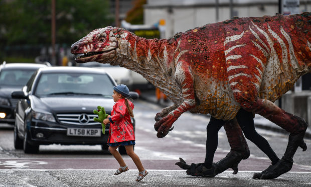 Freya Smith aged three, leads one of Erths giant dinosaur puppets across the road in Edinburgh. Australian theatre company Erth presents their best-selling show Dinosaurs Zoo as part of Underbellys Fringe programme. Featuring giant dinosaur puppets which walk, roar and blink like the real thing, Dinosaurs Zoo is a perfect example of edutainment for children of all ages, taking place at the McEwan Hall every day of the Fringe at 11am.