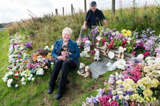 Moira Campbell and her dog, Rusty, with William Robertson, who tends to the grass and flowers at the roadside grave of 'Danny' near Loch Glow