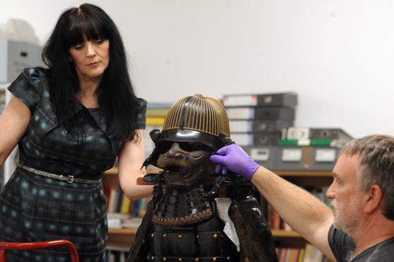 Curator Lesley Lettice and conservator Will Murray work on assembling the striking Japanese samurai suit of armour.