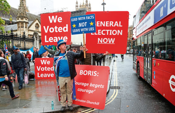 Pro and anti-Brexit supporters hold signs and demonstrate outside Parliament in London.