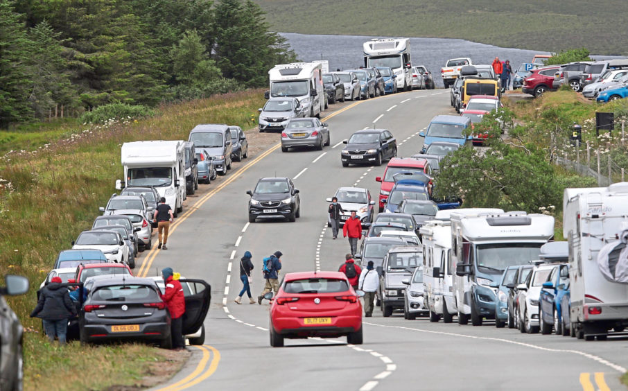 The parking area at the Old man of Stoer on the Isle of Skye, where tourists park on both sides of the road despite the yellow lines.